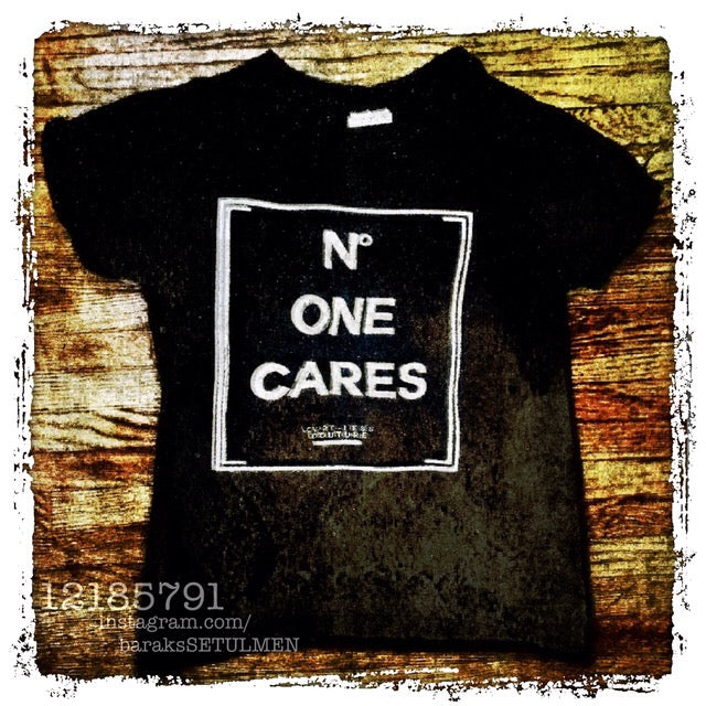 Black t-shirt with 'NO ONE CARES' text on a wooden background