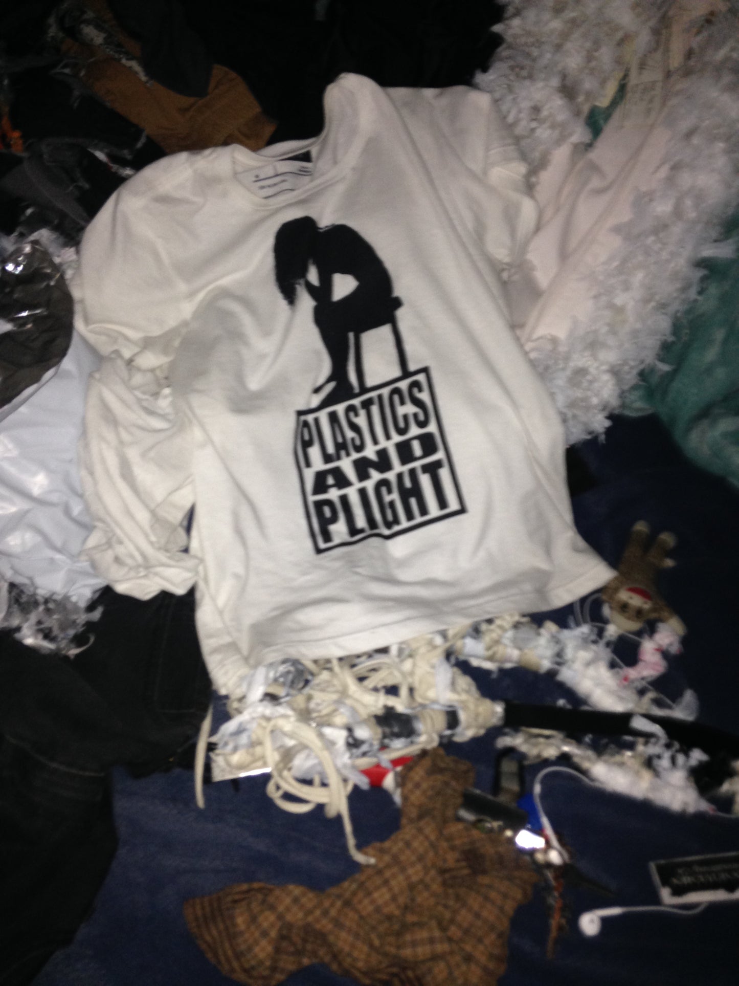 White shirt with black graphic design on a pile of clothes