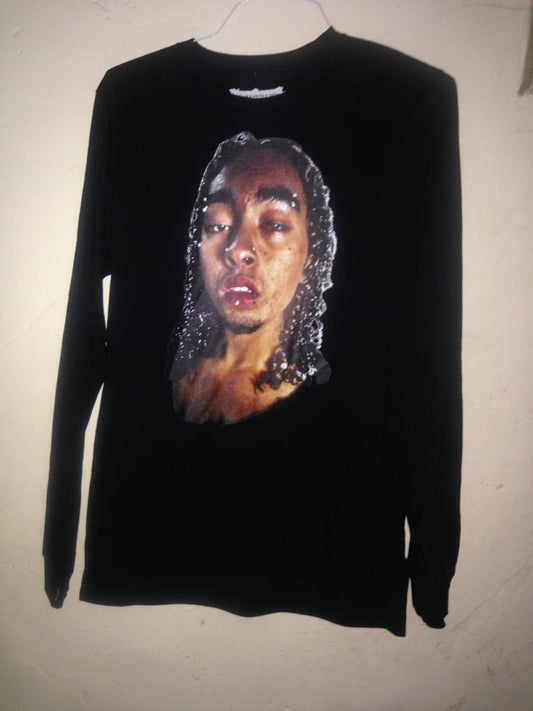 Black long-sleeve
 top with a graphic of a face on a beige background