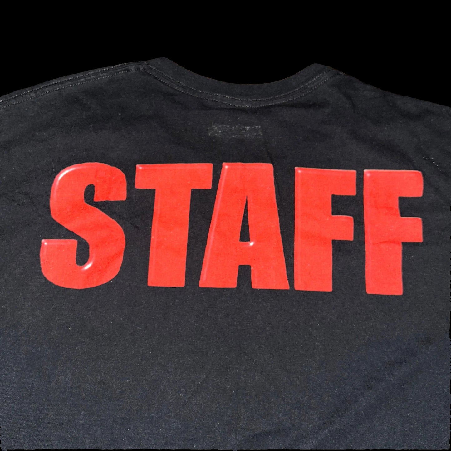 Black shirt with red 'STAFF' text on a wooden surface