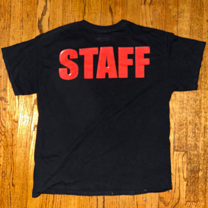 Black t-shirt with 'STAFF' in red on a wooden surface