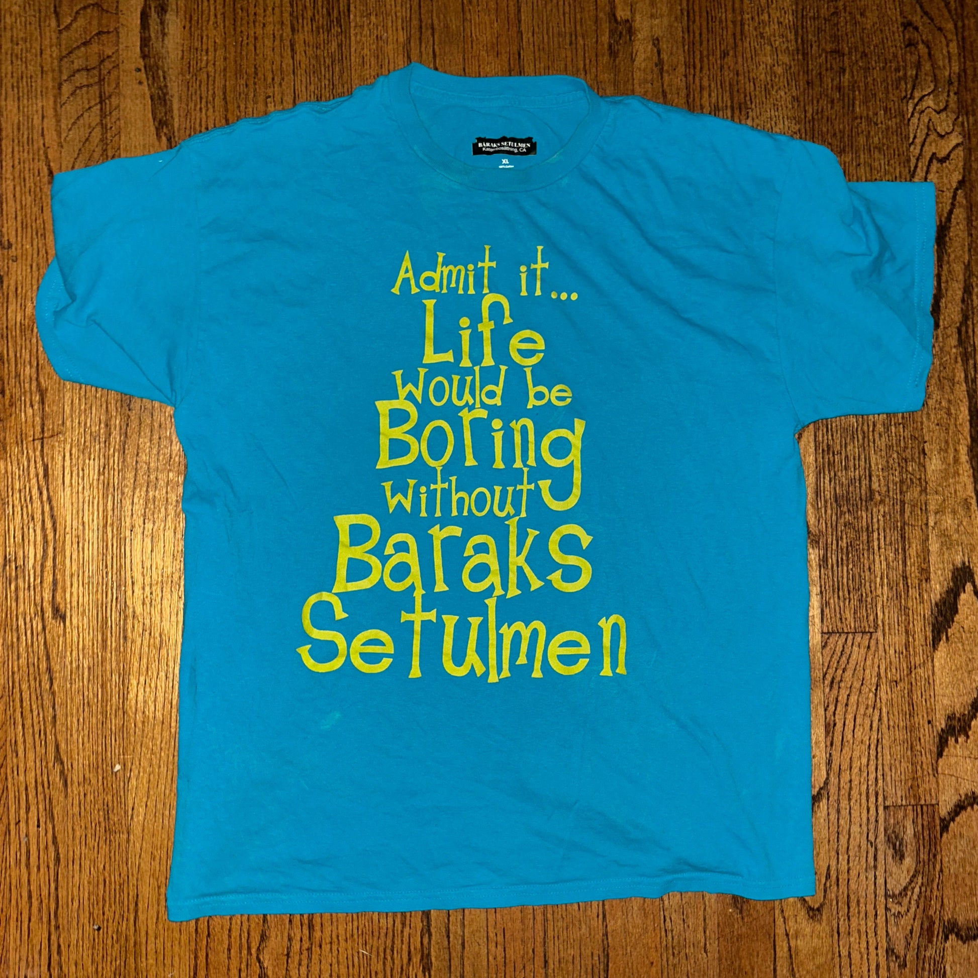 Blue t-shirt with yellow text on a wooden surface
